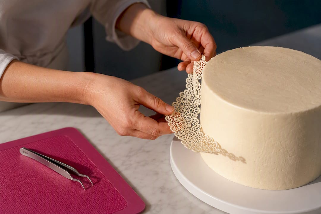 Essbare Spitze wird auf eine Torte gelegt