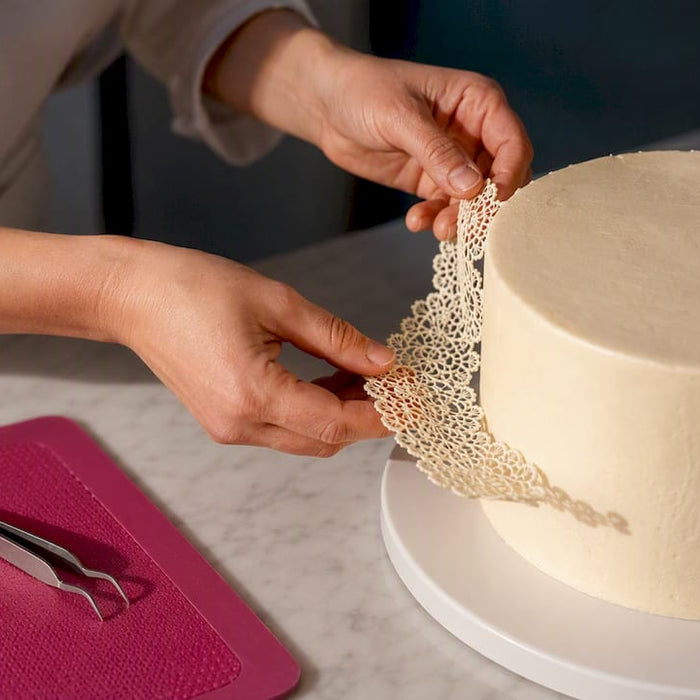 Essbare Spitze wird auf eine Torte gelegt