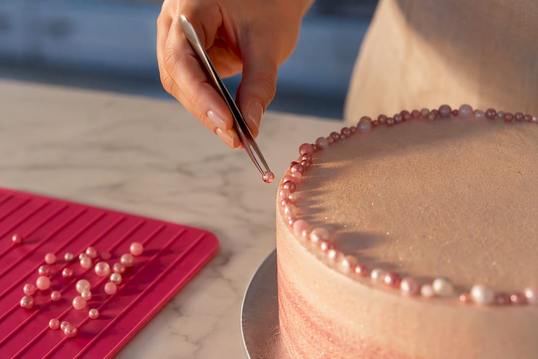 Zuckerperlen werden sorgfältig auf der Torte platziert