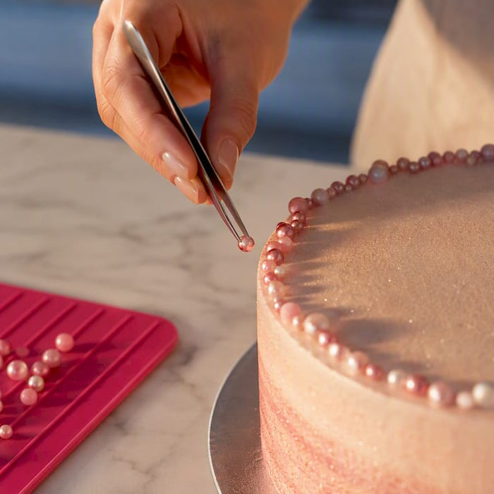 Zuckerperlen werden sorgfältig auf der Torte platziert
