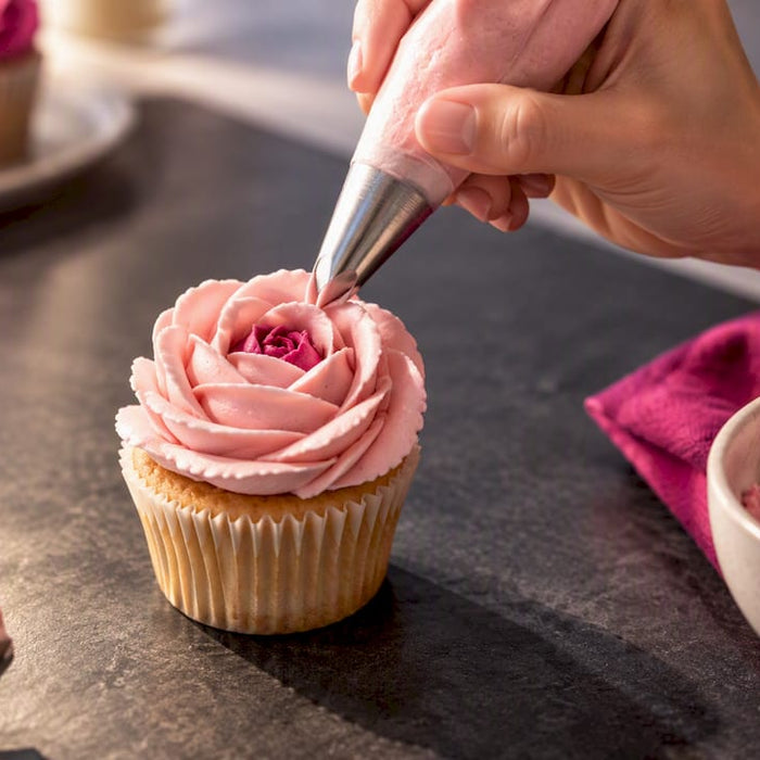 Hand spritzt eine Rose aus Buttercreme