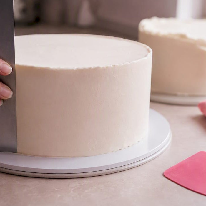 Hand streicht Creme auf eine Torte