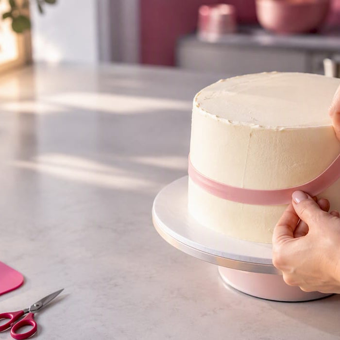 Mit den Händen das Tortenband am Rand der Torte anbringen