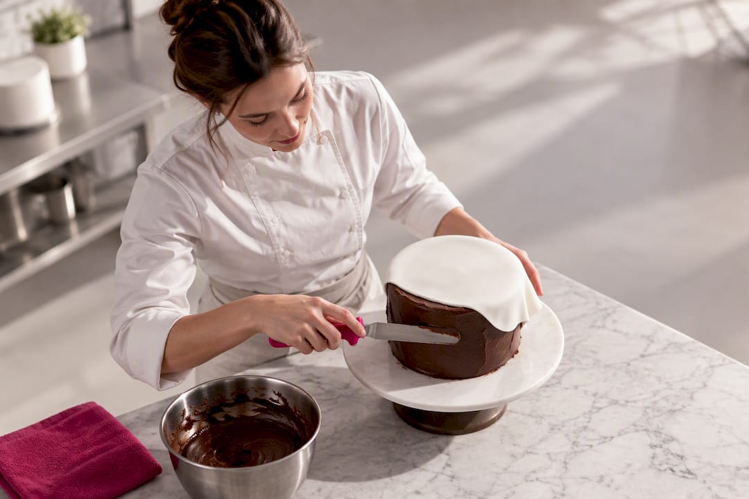 Ganache wird gleichmäßig und glatt unter dem Fondant aufgetragen