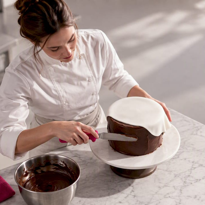 Ganache wird gleichmäßig und glatt unter dem Fondant aufgetragen