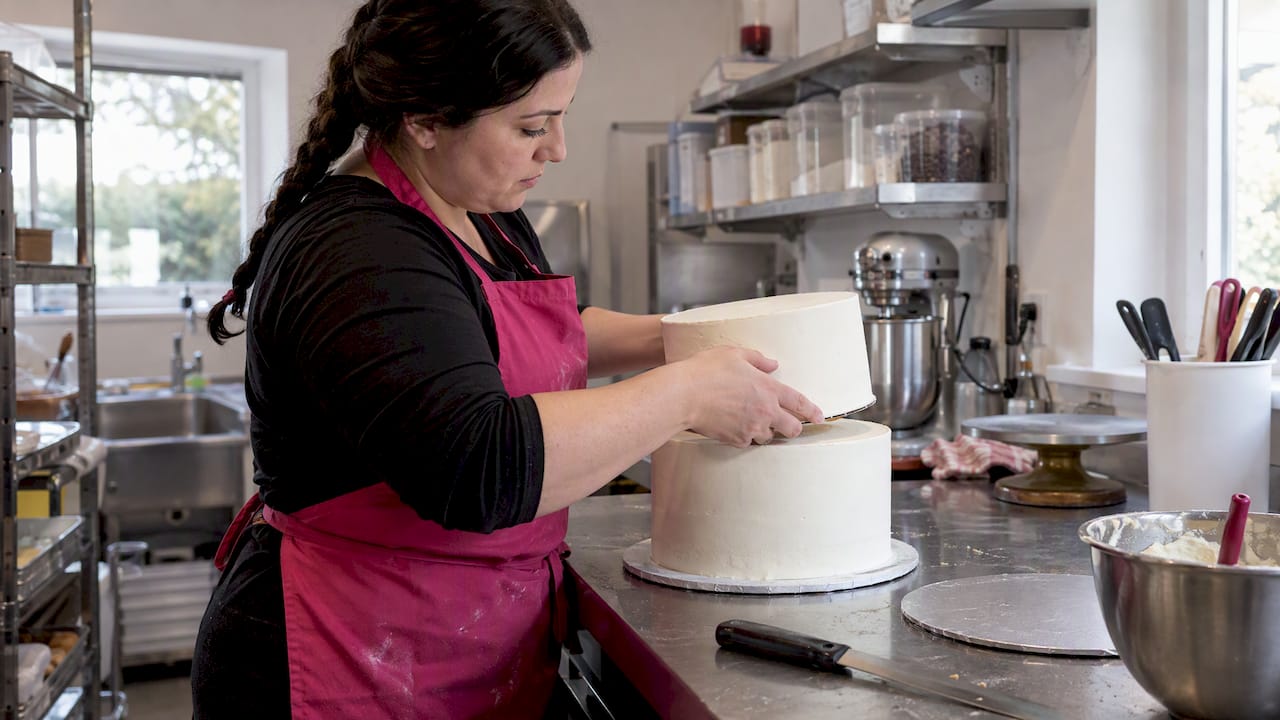 Die Konditorin stapelt eine weitere Ebene auf die Torte.