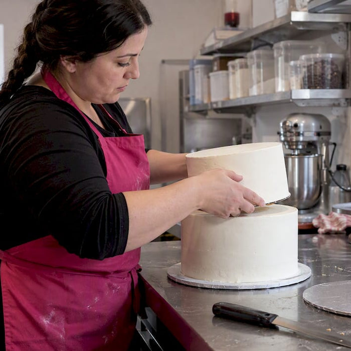 Die Konditorin stapelt eine weitere Ebene auf die Torte.